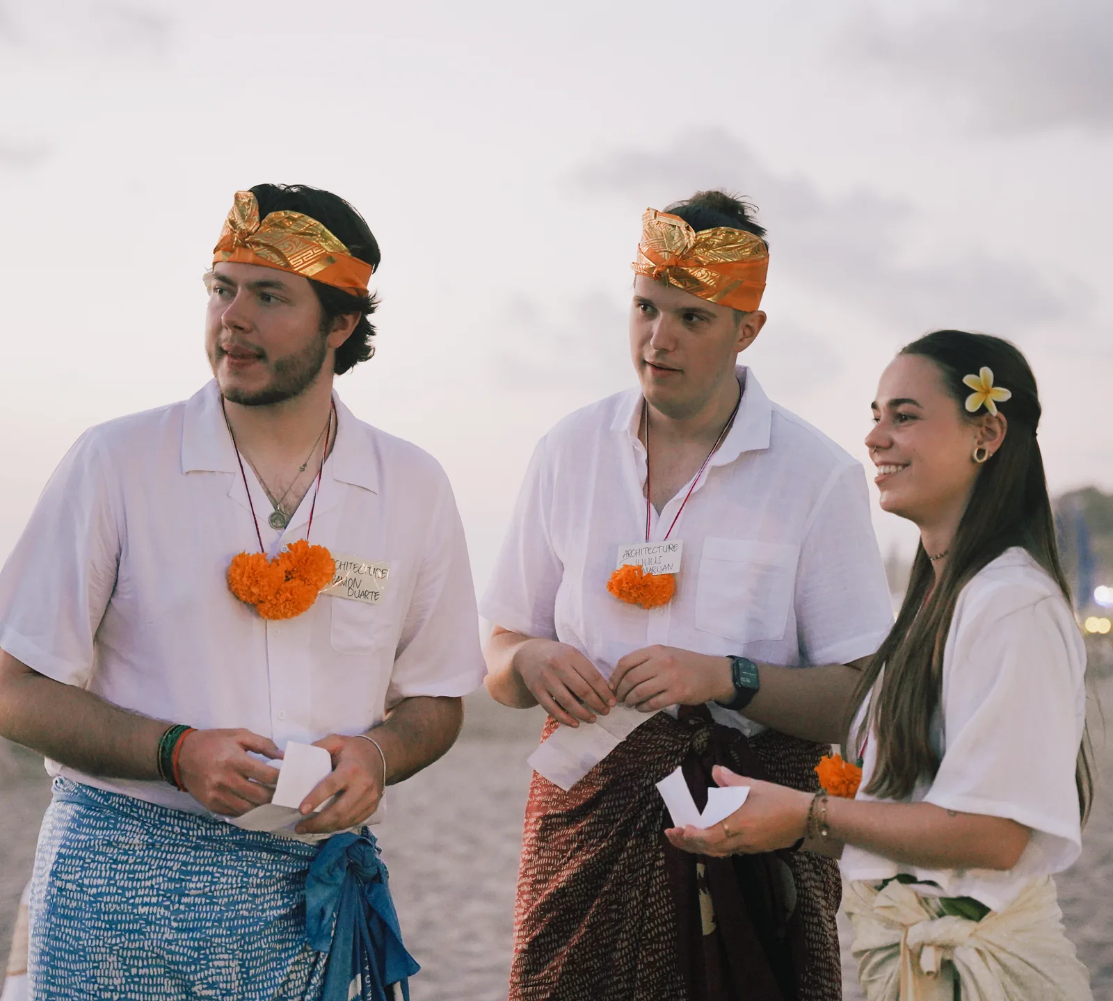 Three architecture students in sarong and udeng waiting for their turn at the microphone